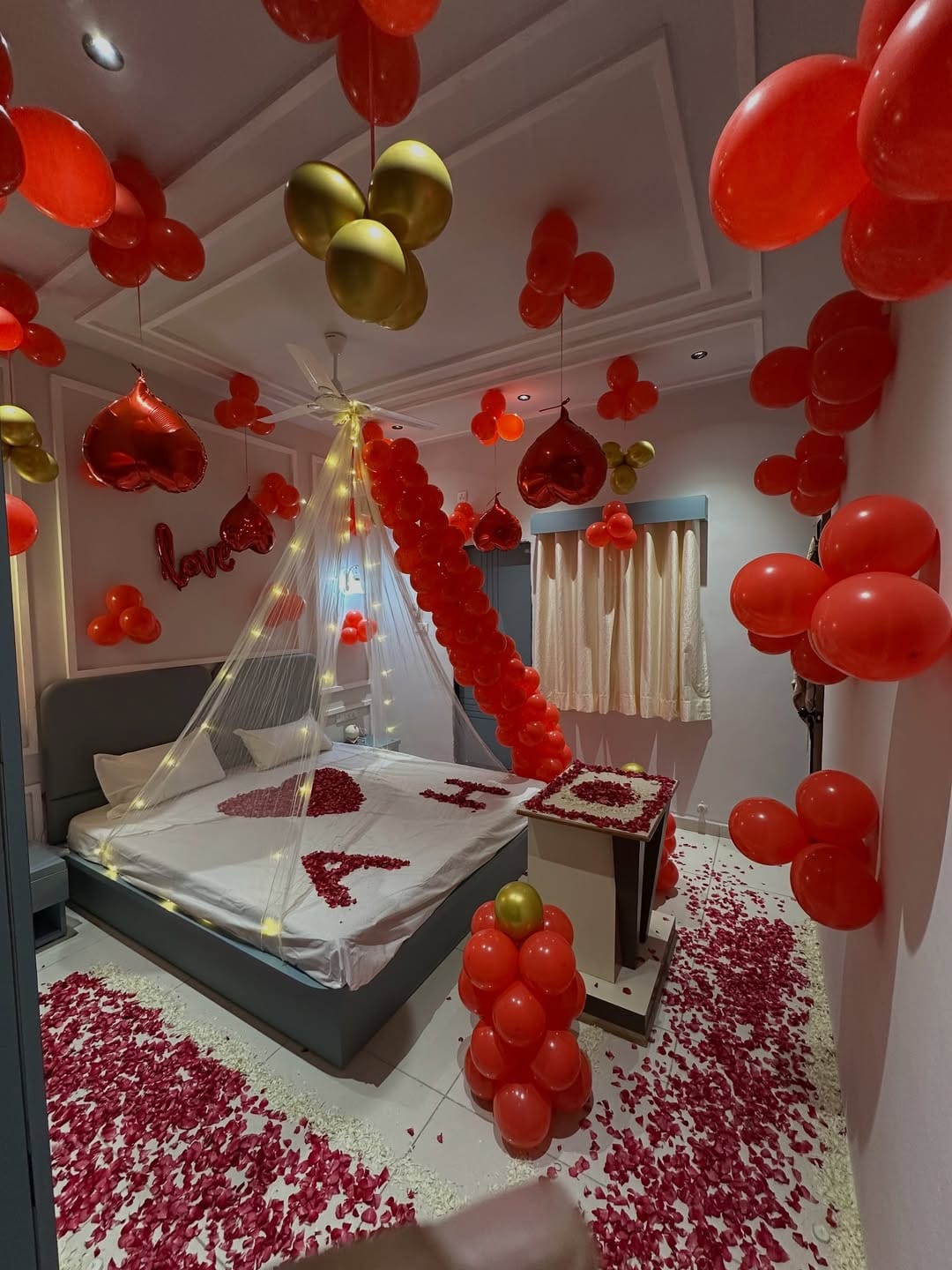 Romantic room decoration with ceiling balloons, fairy lights and petal heart in Ahmedabad